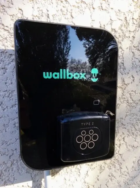 Équipement de recharge installé en extérieur sur le mur d'une habitation