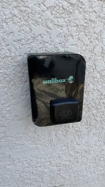 Borne Wallbox Pulsar noire installée sur la façade d'un immeuble pour un résident